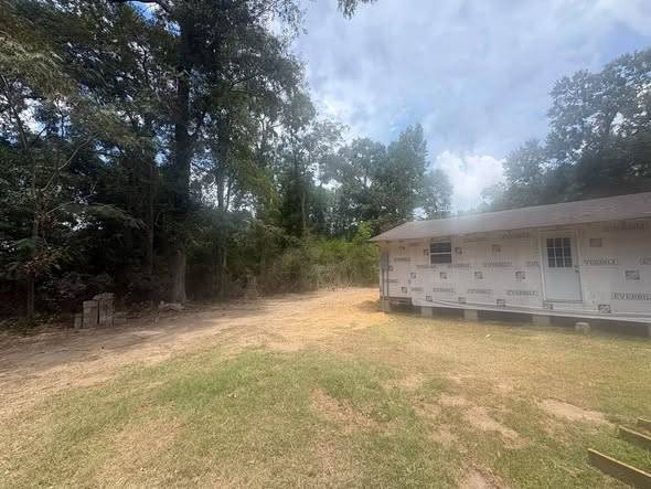 Open cleared ground next to a new house, woods behind