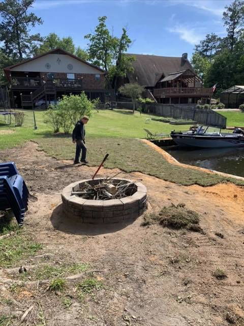 Freshly laid sod and a stone fire pit in a waterfront back yard